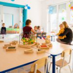 Zdjęcie sali przedszkolnej z dziecmi siedzącymi przy stoliku